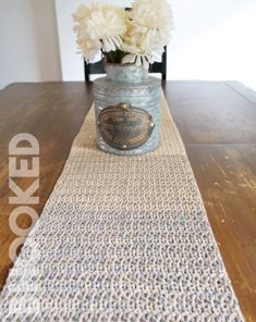 a vase with white flowers sitting on top of a table next to a wooden table