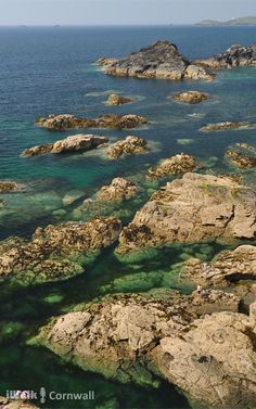 people are standing on the rocks by the water