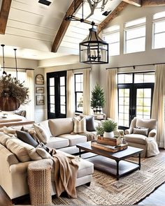 a living room filled with lots of furniture next to two large windows and a chandelier