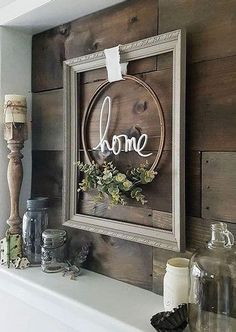 a wooden sign hanging on the wall above a mantle with candles and other items around it