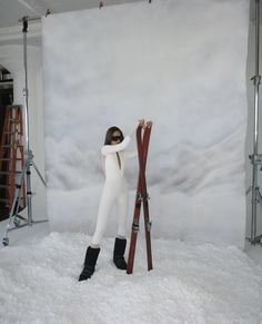 a woman standing in the snow next to skis