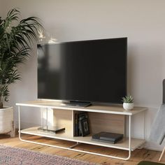 a flat screen tv sitting on top of a white entertainment center next to a chair