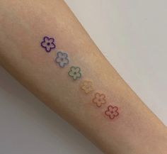 a person with a tattoo on their arm that has four different colored flowers painted on it