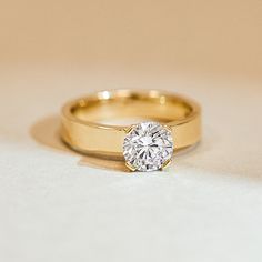 a diamond ring sitting on top of a white countertop next to a gold band