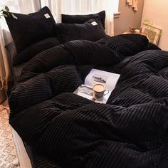 a bed with black comforter and pillows on it