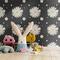 two stuffed animals sitting next to each other in front of a wall with flowers on it