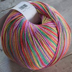 a skein of multicolored yarn sitting on top of a wooden floor