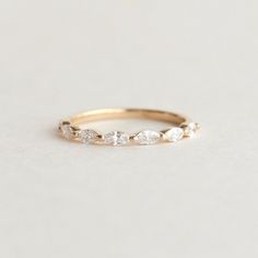 a gold ring with three diamonds on the top and one diamond in the middle, sitting on a white surface