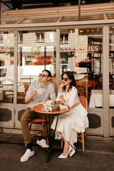 a man and woman sitting at a table in front of a store