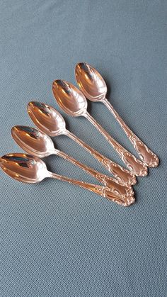 five silver spoons sitting on top of a blue surface