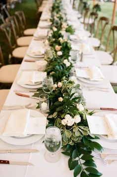 the long table is set with white plates and silverware