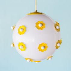 a white ball with yellow flowers hanging from it's side on a blue background