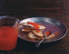 a plate with bread and tomato sauce on it next to a cup of tea or juice