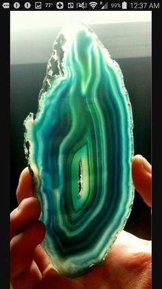 a person holding up a piece of green and blue agate