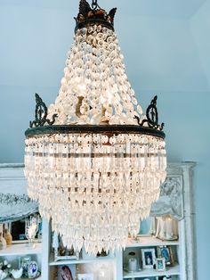 a chandelier hanging from the ceiling in a room with bookshelves and pictures