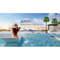 a woman sitting on the edge of a swimming pool in front of a city skyline