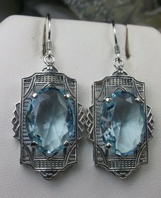 "Simulated Aquamarine Earrings Braid Design#E19 Custom Made Inspired by the Art Deco movement of the early 1900s, I now offer these lovely Antique reproduction earrings in sterling silver. Each stunning 8ct flawless Simulated Blue aquamarine is 16mm long (just over 5/8th\") and 12mm in width (1/2\"). The aquamarines have perfect color and clarity. The earrings are 1 3/4th inches long. Notice the beautiful design of the Deco filigree setting. These earrings were fashioned from an Art Deco 1930s b Oval Art Deco Earrings For Formal Occasions, Art Deco Oval Earrings For Formal Occasions, Art Deco Hallmarked Drop Earrings, Formal Oval Art Deco Earrings, Hallmarked Art Deco Earrings For Anniversary, Art Deco Sterling Silver Earrings For Formal Occasions, Art Deco Pierced Jewelry For Anniversary, Art Deco Hallmarked Earrings As Gift, Blue Art Deco Drop Earrings