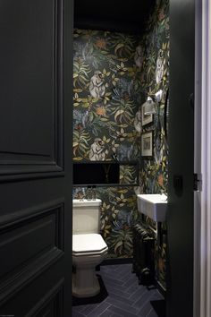 an open door leading to a bathroom with floral wallpaper