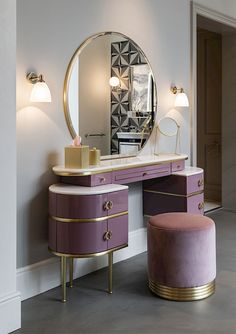 a vanity with a mirror, stool and lamp in a room that has white walls