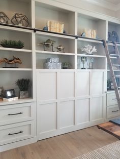 a living room with white bookcases and shelves