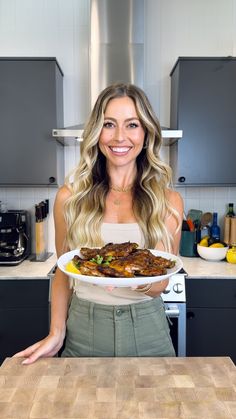 a woman holding a plate of food in her hands while standing next to a kitchen counter