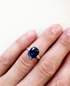 a person's hand with a ring on it and a blue stone in the middle