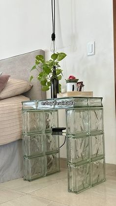 a glass side table with plants on it in front of a bed and a couch