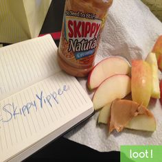 an open notebook sitting on top of a table next to apples and other food items