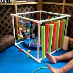 a man sitting on the floor next to an array of colorful candles and beads in a cage