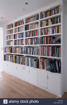 a bookshelf filled with lots of books in an empty room