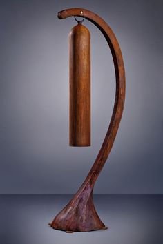 a wooden sculpture with a long neck and curved handle on the top, in front of a gray background