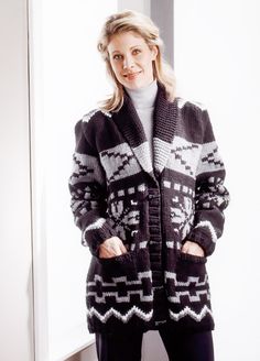 a woman standing in front of a window wearing a black and white knitted cardigan