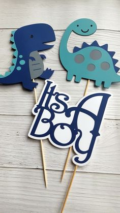 three dinosaur cupcake toppers with the words it's a boy on them