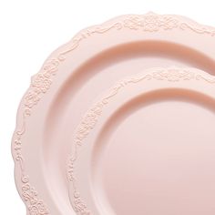 three pink plates sitting side by side on top of each other, one with an ornate design