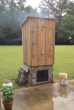 a small wooden outhouse sitting in the middle of a yard with potted plants next to it