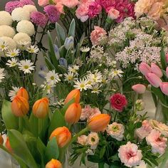 a vase filled with lots of different colored flowers next to each other on a table