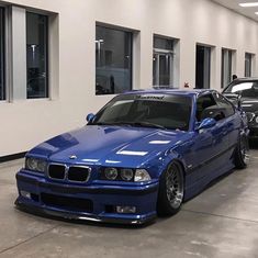 two cars parked in a garage next to each other near one another with windows on the wall