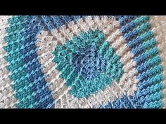 a crocheted blanket is shown with blue and white squares on the bottom half