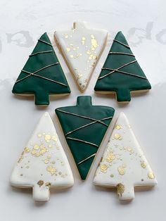 four decorated cookies with green and white icing in the shape of christmas trees on a table