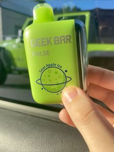 a hand holding an apple ice drink in front of a green car window with the word geekbar on it