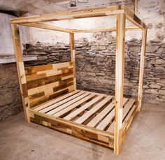 a bed made out of pallet wood in a room with stone walls and flooring