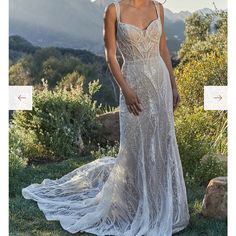 a woman in a wedding dress standing on the grass with mountains in the back ground