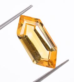 an orange diamond is being cut into smaller pieces with two needles in front of it