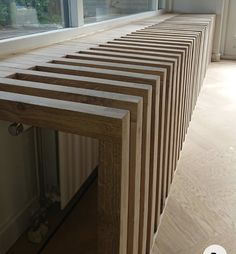 a wooden bench sitting in front of a window next to a hard wood flooring