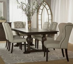 a dining room table with chairs and a mirror