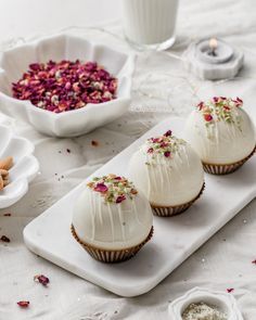 three cupcakes with white frosting and sprinkles on a tray