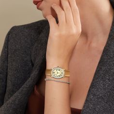 This oval-shaped watch features a gold-plated steel case adorned with a ring of white transparent trapezoid cut lab-grown gemstones. The orange pebbled leather strap complements the dial, which includes two lab-grown diamonds. The dial showcases classic Roman numerals set against a radiant golden metallic backdrop. This piece elegantly blends vintage charm with modern sophistication, embodying both elegance and avant-garde style. Case: 24mm steel case with polished and satin finish. Movement: Sw Gold Jewelry Watch With Rectangular Dial And Bracelet Strap, Gold Watch With Bracelet Strap And Rectangular Dial, Gold Diamond Watch With Rectangular Dial And Polished Finish, Timeless Yellow Gold Watch Accessories, Yellow Gold Bracelet Strap Watch, Elegant Yellow Gold Jewelry With Rectangular Dial, Modern Gold Jewelry And Watches, Modern Everyday Luxury Jewelry With Round Dial, Elegant Gold Watches With Subdials