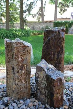 three large rocks sitting on top of a rock covered ground