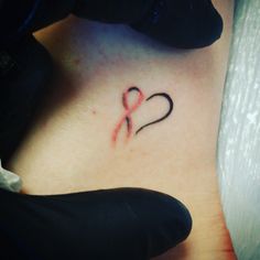 a small heart tattoo on the back of a woman's left arm, with an arrow