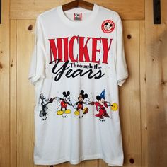 a mickey mouse shirt hanging on a wooden wall with the words mickey through the years printed on it